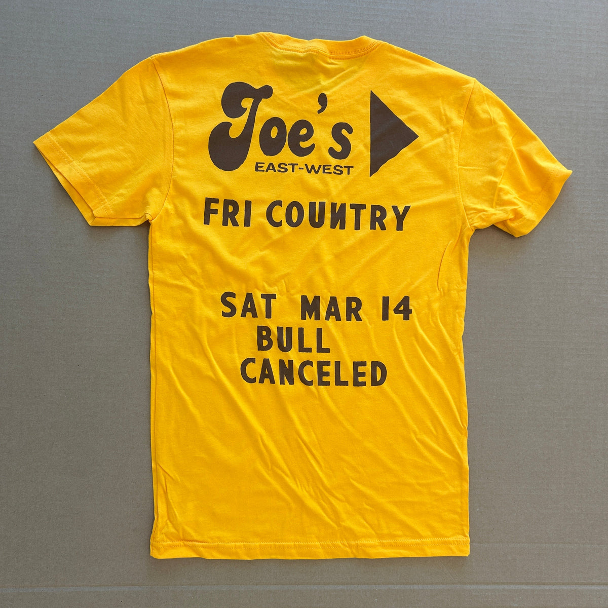 Yellow t-shirt with black text and logo on a gray background